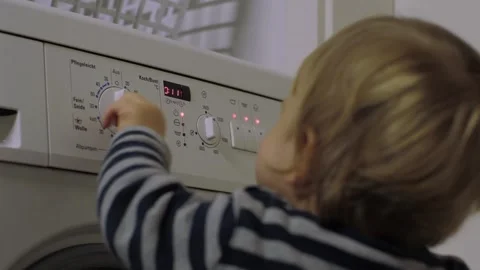 A toddler selects a program on a washing machine Video stock 322682153