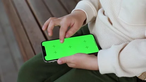 A toddler sits on a banch and scrolling the phone Stock Footage 246238181
