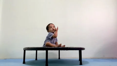 Toddler sitting and playing on a small indoor trampoline Stock Footage 341497805