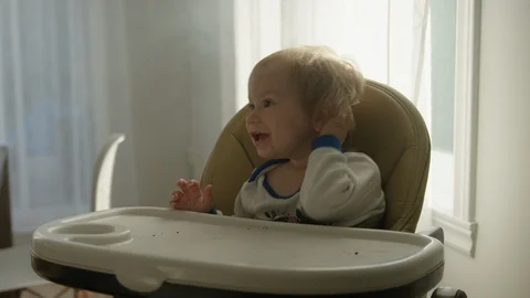 Toddler sitting on high chair in dining room at home Stock Footage 119992653