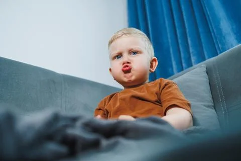 Toddler sitting on sofa expressing creativity through gestures. Young child o Foto stock