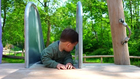 Toddler sliding down a slide backwards. Toddler having fun. 库存影片 334679917