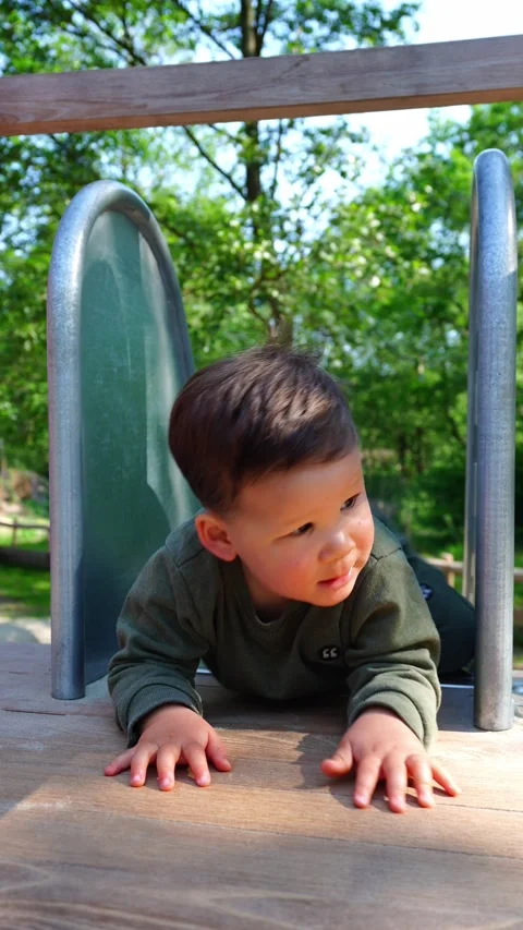 Toddler sliding down a slide backwards. Toddler having fun. 库存影片 334680081