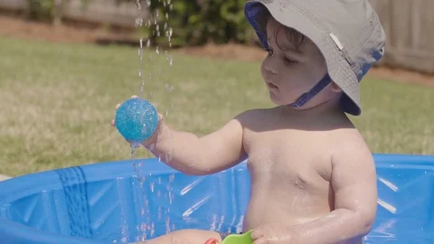 Toddler in Small Pool Plays with Ball Stock Footage 90224463