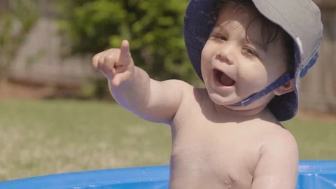 Toddler in Small Pool Points and Smiles at Camera Stock Footage 90224426
