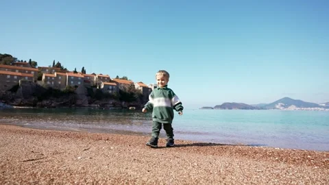Toddler strolls on pebble beach Stock Footage 243296022
