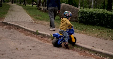 Toddler successfully overcomes an obstacle in the form of a curb on the bike Stock Footage 243415029