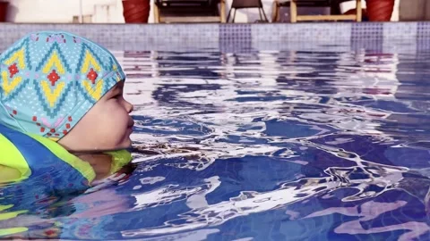 Toddler swimming in a pool wearing a flotation vest and swim cap Stock-Footage 340808726