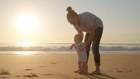 Toddler takes the first steps with caring mother. Mom teaches her baby to w.. Stock Footage 303585090