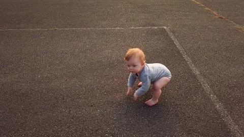 Toddler takes first steps falls on butt rises to get back up. Determined Stock Footage 117469073