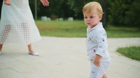 Toddler takes first steps guided by adult hand 動画素材 348269230