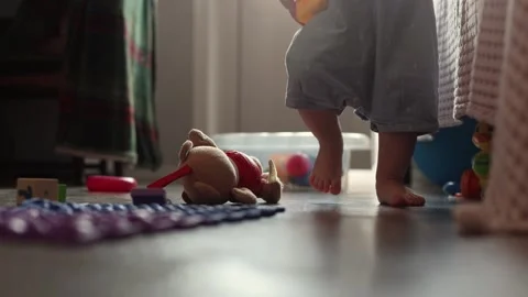 Toddler taking first steps on a wooden floor in a cozy home environment during Stock Footage 345643271