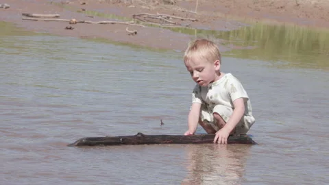 Toddler Throws Big Stick into River and is Happy Stock Footage 328276658