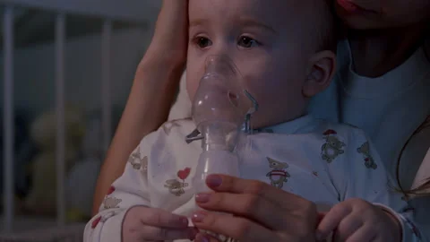 Toddler undergoing inhalation therapy during cold season, captured in a cozy Stock Footage 323232648