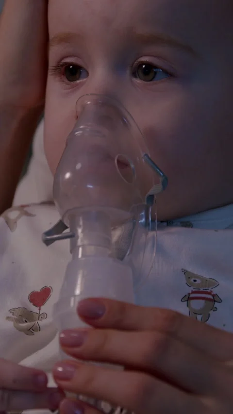 Toddler undergoing inhalation therapy during cold season, captured in a cozy Stock Footage 323497915