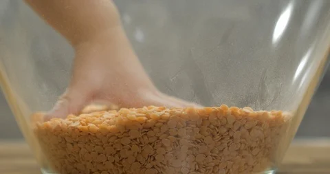 Toddler using bare hand to play with lentil seeds Stock Footage 99952176