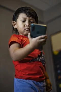 Toddler Using Smartphone To Call His Mother In The Room Stock Photos
