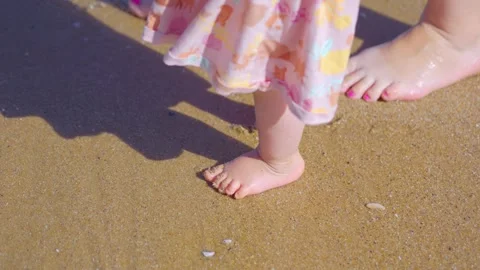 Toddler walking on sandy beach, waves touching feet, sunny day in 4k slow motion Stock Footage 266508498