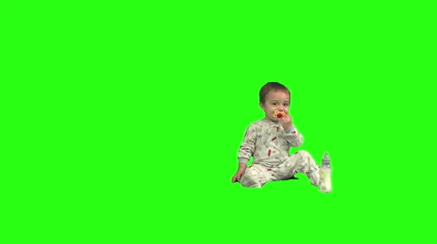 Toddler walks onscreen from left and sits next to his bottle. Green background. Stock Footage 49864485