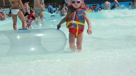 Toddler walks toward camers pulling her inner tube Stock Footage 64531884