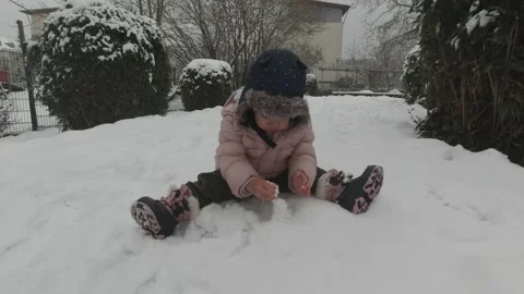 Toddler in winter clothes touching exploring snow texture Stock Footage 147391442