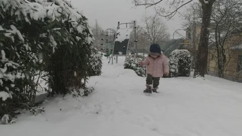 Toddler in winter jacket and winter hat walking in the snow Stock Footage 147391285