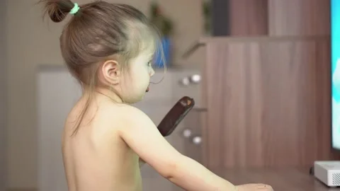 Toddler without clothes eats ice cream in chocolate and watches tv Stock Footage 153132616