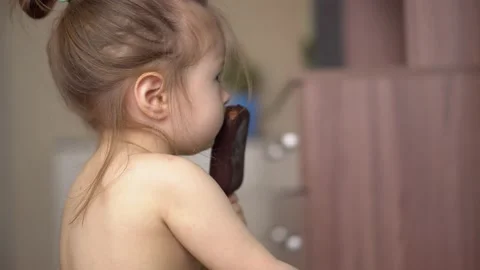 Toddler without clothes eats ice cream in chocolate and watches tv Stock Footage 153132659