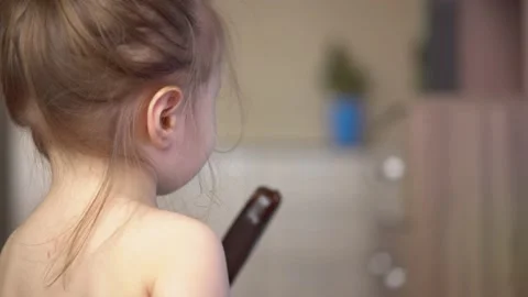 Toddler without clothes eats ice cream in chocolate and watches tv Stock Footage 153132702