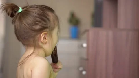 Toddler without clothes eats ice cream in chocolate and watches tv Stock Footage 153132836