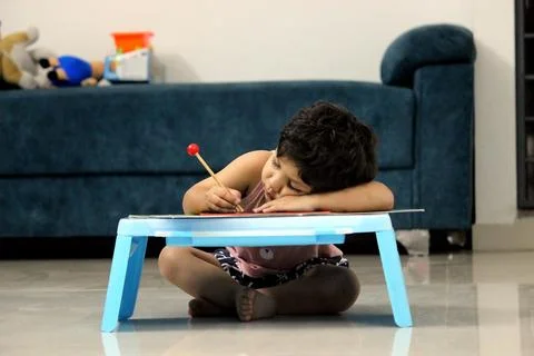 Toddler is writing on a pad, doing Homework, school student, tired, Stock Photos