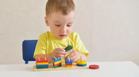 Toddlerboy plays constructor while sitting at a white table. educational game Stock Photos