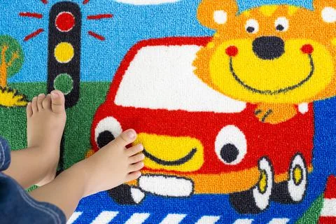 Toddler's feet using a cute patterned doormat. Stock Photos