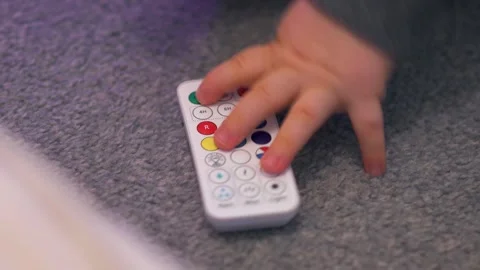 Toddler’s Hand Pressing Remote Button on Carpet: Close-Up Stock Footage 325131405