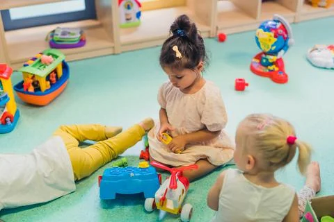 Toddlers playing with a plastic shape sorter toy, a colorful helicopter, boats Stock Photos