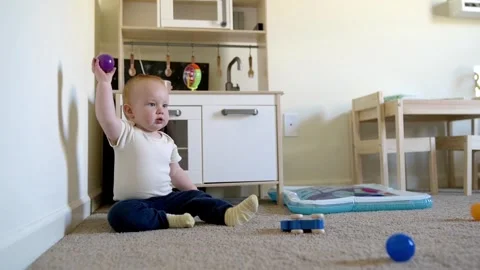 Todler, one year old, a red-haired boy, sitting in the children's room on the Видео 270198874