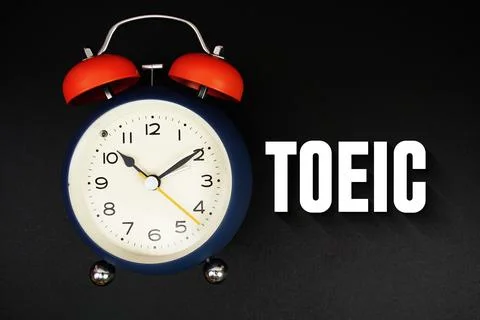 TOEIC text with alarm clock on black background Stock Photos