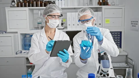 Together in the trenches, two scientists, donned in gloves and masks, scrib.. Stock Footage 262770539