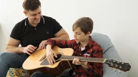 Togetherness in learning how to play guitar between father and his son front Stock Footage 112557719