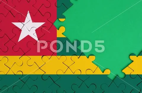 Togo flag is depicted on a completed jigsaw puzzle with free green copy spac Stock Photos