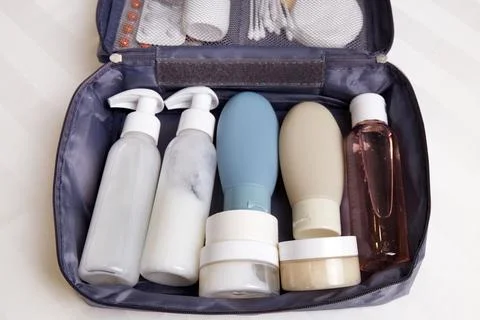 A toiletry bag is open on a flat surface, showcasing neatly arranged bottle.. Stock Photos