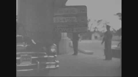 TOKYO - 1953: Compound view - Saluting figure appears beyond a parked car Stock Footage 344500553
