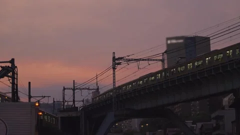 Tokyo commuter train crossing an elevated railway bridge at sunset Stock Footage 340644727
