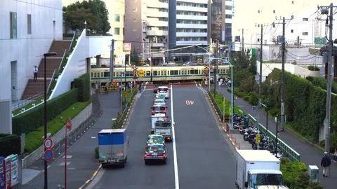 Tokyo Japan - Train Passing By At Level crossing While Cars Wait Behind Barrier Stock Footage 97983687