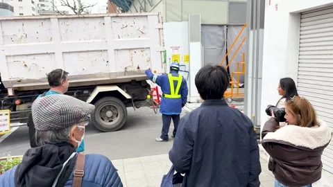 Tokyo Pedestrians Wait as Security Guard Directs Truck at Construction Site Stock Footage 335851558