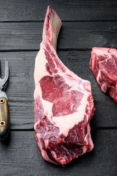 Tomahawk beef steak raw, on black wooden table background Stock Photos