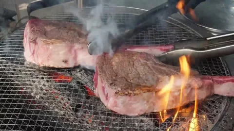 Tomahawk Beef Steaks Grilling on Barbecue Charcoal Grill with Flames and Smoke Stock Footage 338210863