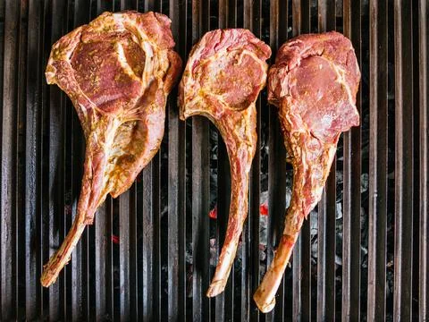 Tomahawk rib beef steak on hot black grill with flames Stock Photos