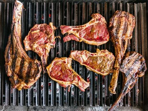 Tomahawk rib beef steak on hot black grill with flames Stock Photos
