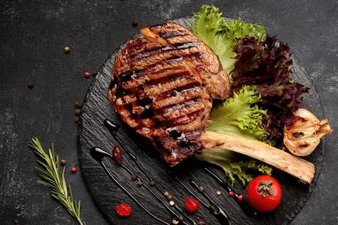 Tomahawk steak on the bone on black slate Stock Photos